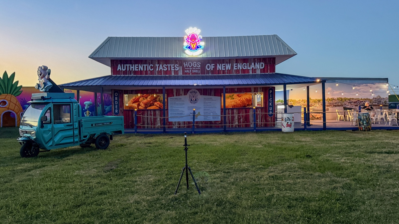 The 2026 Hogs on the Half Shell booth glowing at dusk — winner of 1st Place Booth Design