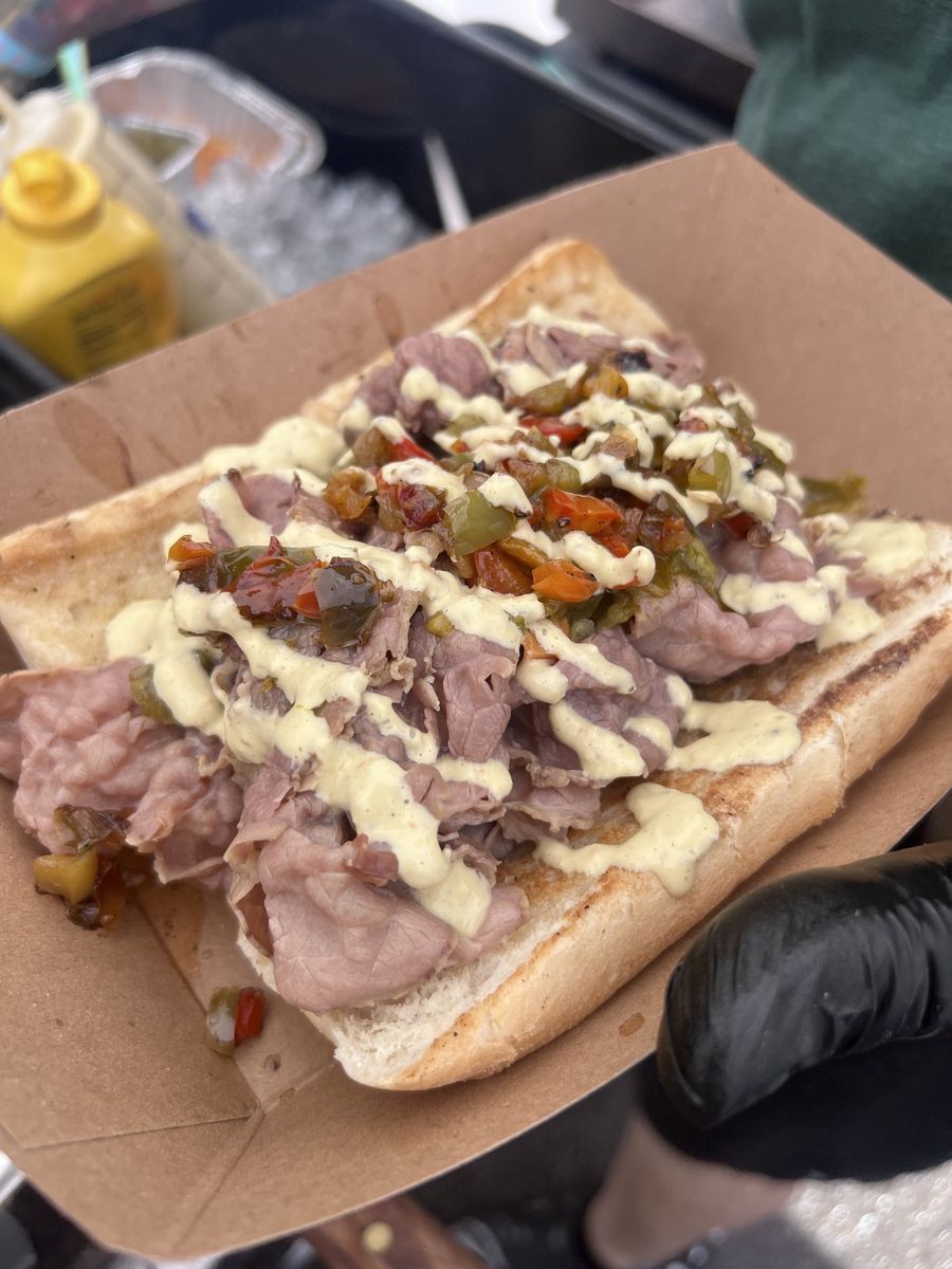 An Italian beef piled with giardiniera, sweet peppers, and a cheese drizzle