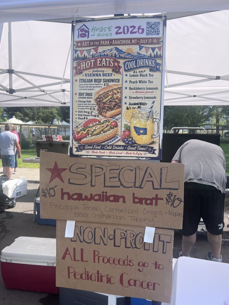 Booth signage: the 2026 menu poster, the Hawaiian brat special, and a sign reading ALL proceeds go to Pediatric Cancer